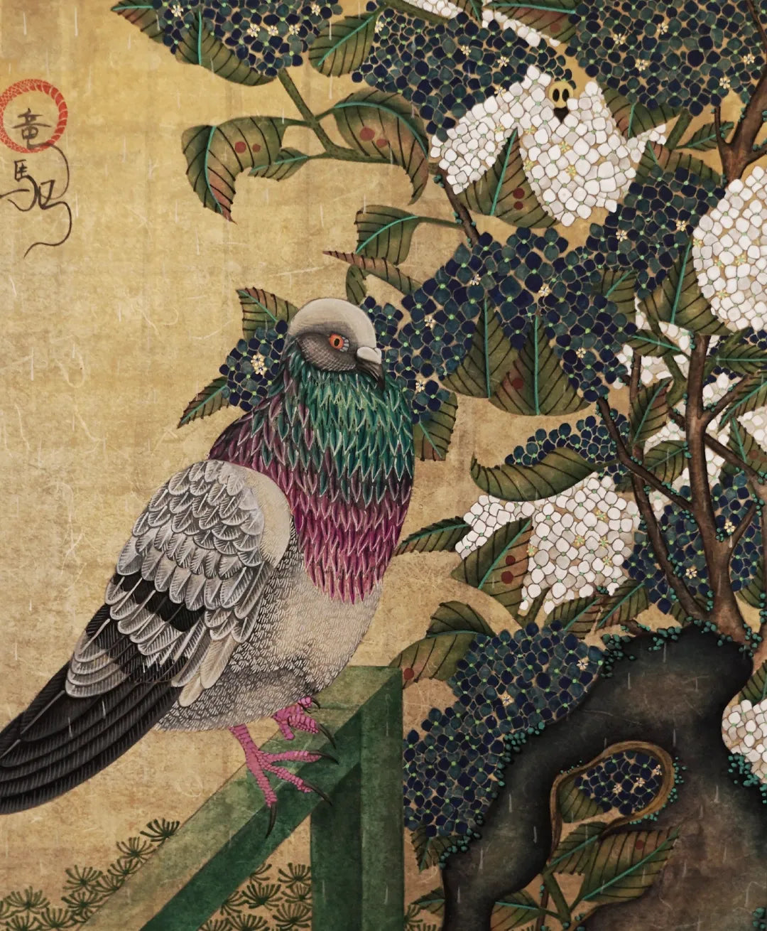 A full-view Japanese Nihonga art print titled "vitality" by Ryuku Otsuka. The composition features a beautifully detailed grey pigeon with iridescent green and purple neck feathers perched on a dark green railing. The bird is set against a lush backdrop of white and dark blue hydrangeas clinging to textured garden stones, painted with a quiet, slow-living dedication on a warm, textured gold-toned background.